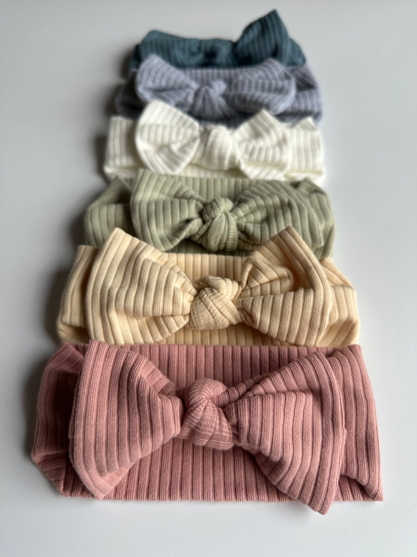 Set of 6 baby bow headbands lined up in a row on a white background