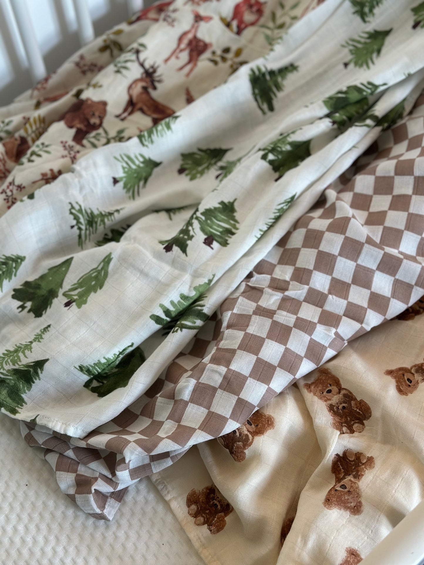 4 patterned muslin swaddle blankets laid out in cot