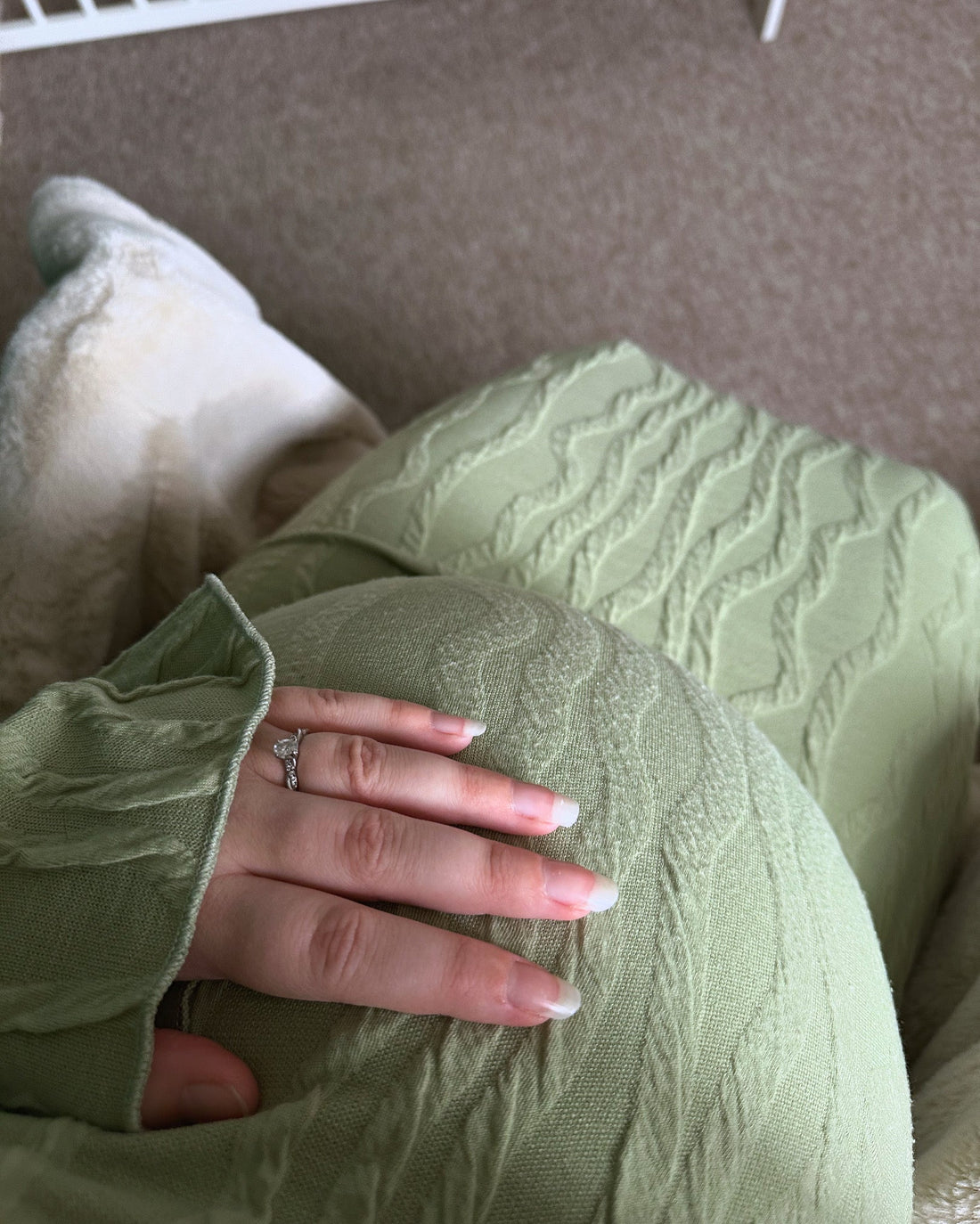 Pregnant lady wearing long green dress with hand on baby bump