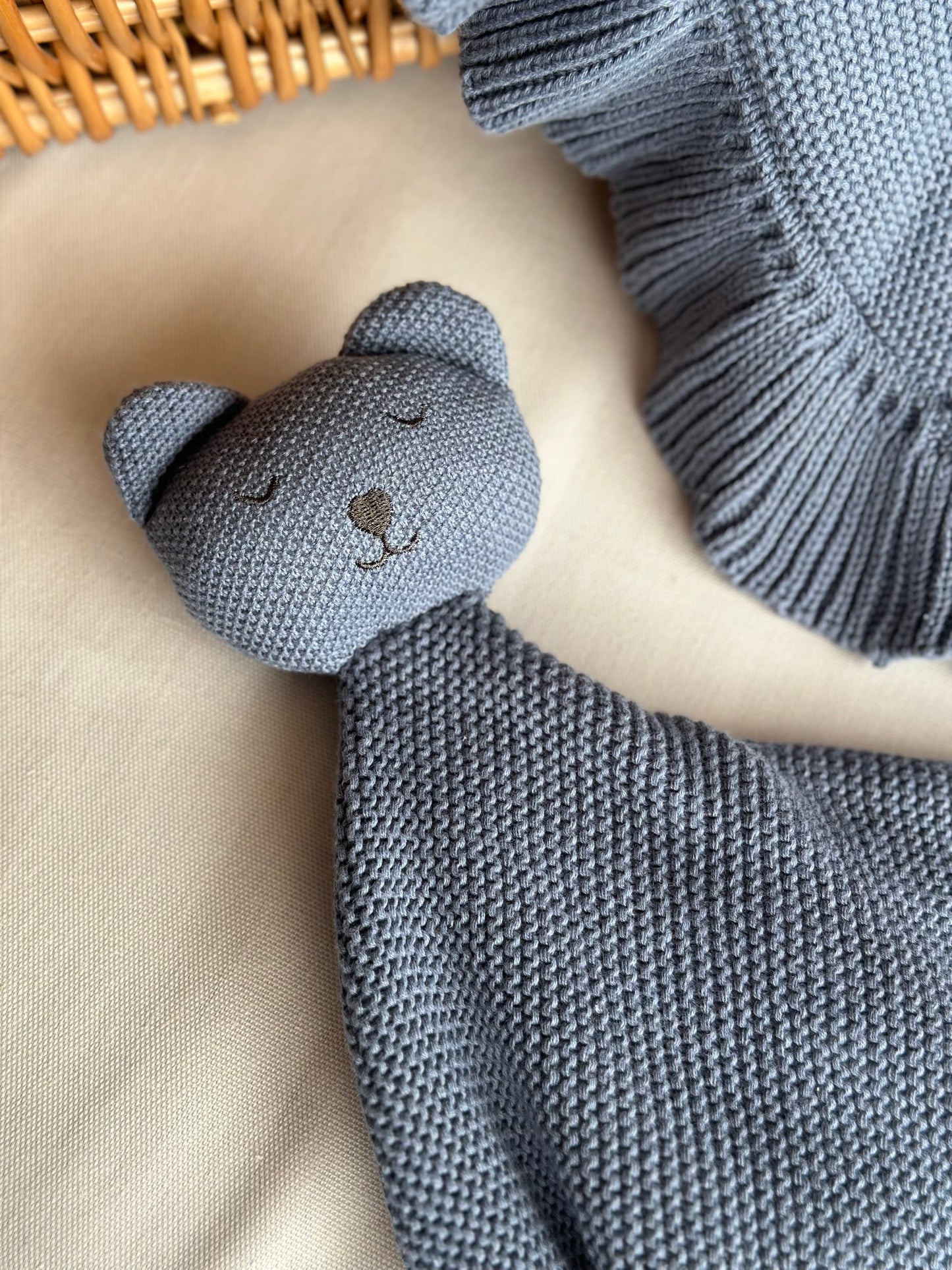 Navy bear comforter laid out on a beige sheet next to the blue matching blanket
