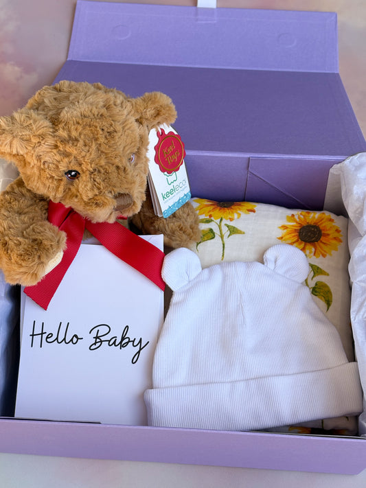 Purple gift box filled with 4 baby items, including a sunflower blanket and teddy bear