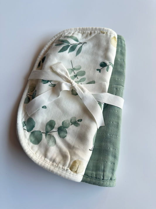 2 muslin burp cloths wrapped in a white bow laid on a white background